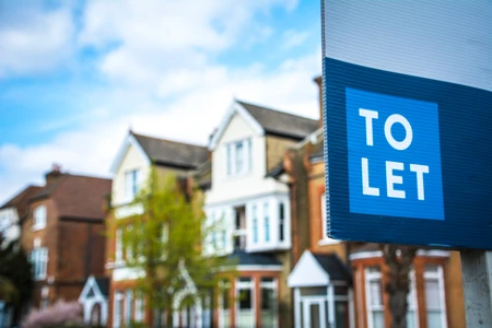 Estate agency 'To Let' sign board with large typical British houses in the background