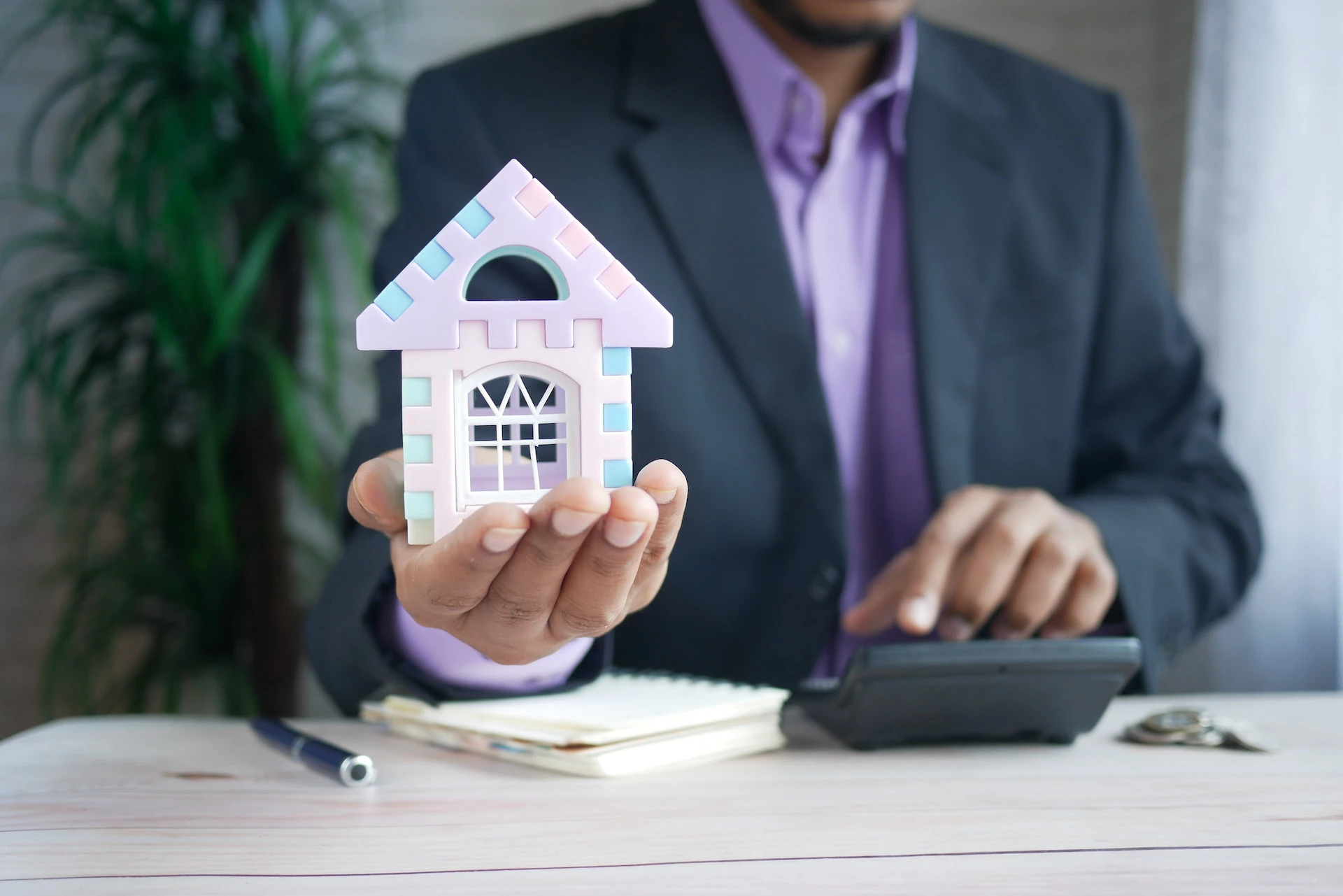 Man in business suit holding a model house