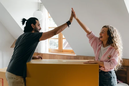 Couple high-fiving over a large cardboard box
