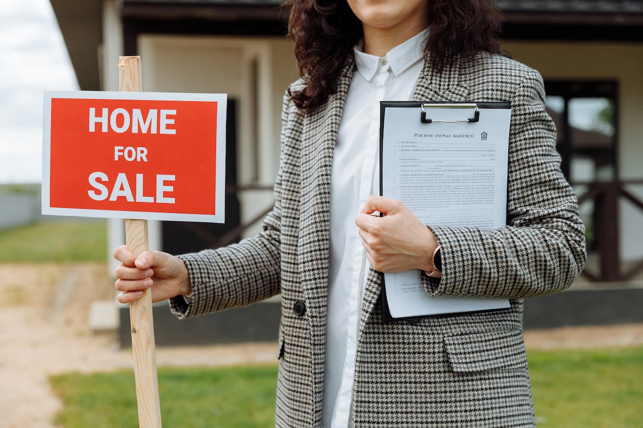 Estate Agent Holding Home For Sale Sign 